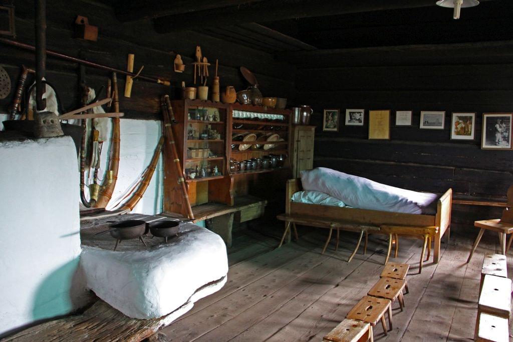Tak zwana izba kurna., gdzie znajduje się „kurlawy”, czyli dymny piec. W pomieszczeniu widoczne
łoże oraz sprzęty kuchenne i tradycyjne instrumenty muzyczne.