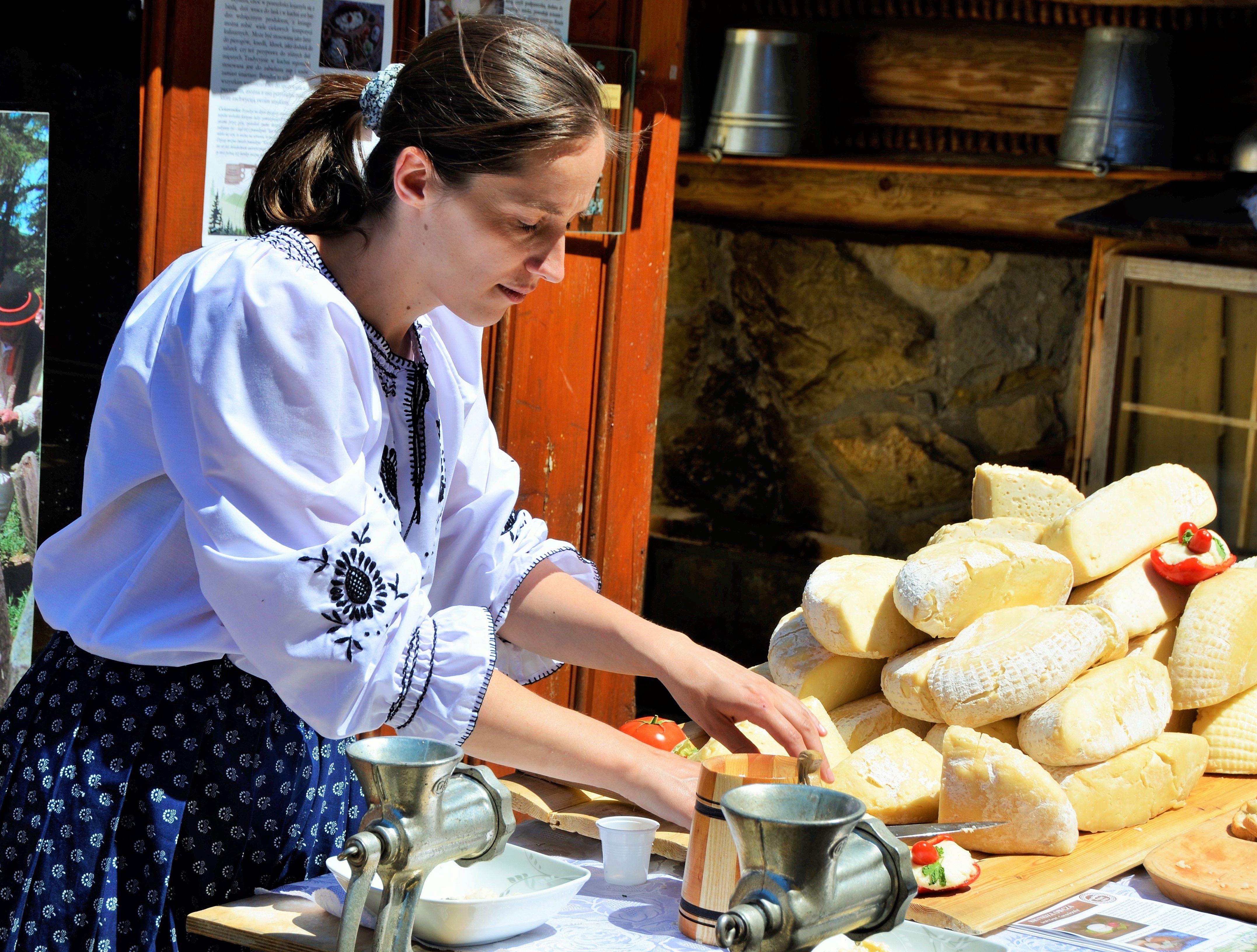 Kobieta w stroju góralskim prezentuje tradycyjną metodę wyrobu sera owczego.